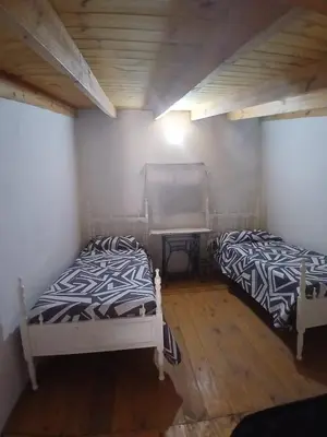 two beds in a room with white walls and wooden floors at Apart La Jose in Río Cuarto