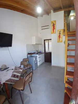 a living room with a table and chairs and a kitchen at Apart La Jose in Río Cuarto