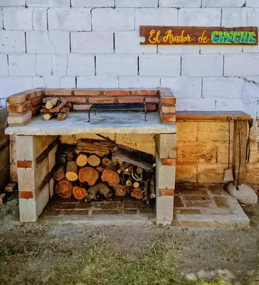 a wooden bench sitting next to a wall with logs at María Reina De La Paz in Villa Cura Brochero