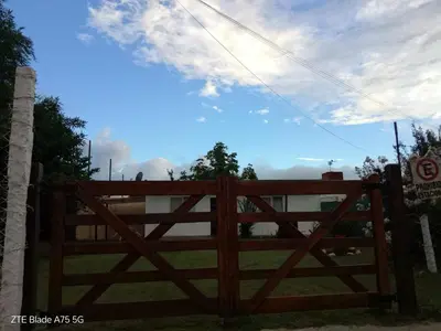 a wooden gate in a field with a cloudy sky at María Reina De La Paz in Villa Cura Brochero