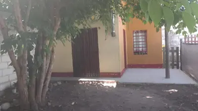 a building with a gate and two trees in front of it at Departamento mina clavero in Mina Clavero