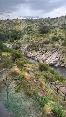 a bench sitting on a hill next to a river at Villa Pellegrini in Trapiche