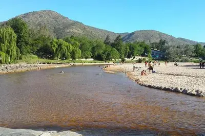 a group of people on a beach near a river at La casa del Sapo Pepe Carlos Paz in Cordoba