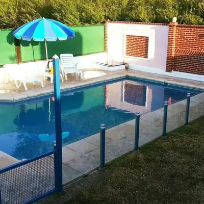 a swimming pool with an umbrella and a table and chairs at La casa del Sapo Pepe Carlos Paz in Cordoba
