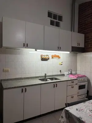 a kitchen with white cabinets and a sink at La casa del Sapo Pepe Carlos Paz in Cordoba