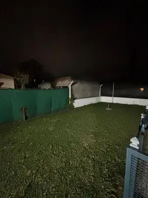 a backyard at night with a green wall and grass at La casa del Sapo Pepe Carlos Paz in Cordoba