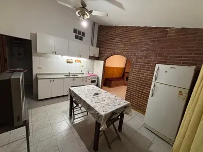 a kitchen with a table and a white refrigerator at La casa del Sapo Pepe Carlos Paz in Cordoba