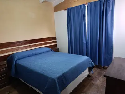 a bedroom with a blue bed and blue curtains at Cabañas EL VALLE in San Ignacio