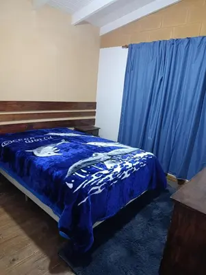 a bedroom with a blue bed and a blue curtain at Cabañas EL VALLE in San Ignacio