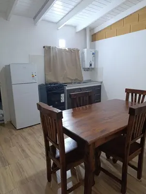 a kitchen with a wooden table and a refrigerator at Cabañas EL VALLE in San Ignacio