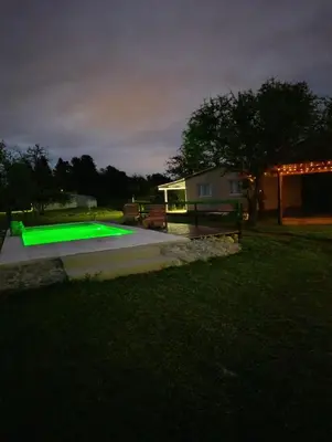 a backyard with a green pool at night at Cabañas EL VALLE in San Ignacio