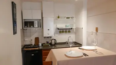 a kitchen with a table with two wine glasses on it at Kalimera Loft con patio, único en Córdoba Capital in Cordoba