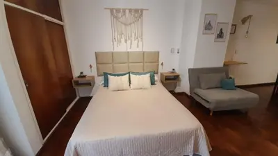 a bedroom with a large bed and a chair at Kalimera Loft con patio, único en Córdoba Capital in Cordoba
