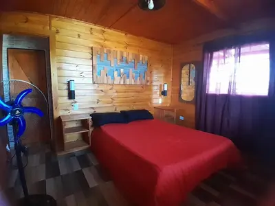 a bedroom with a red bed in a wooden cabin at Cabaña de montaña potrero de garay in Potrero de Garay