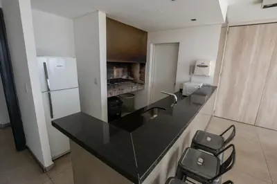 a kitchen with a black counter and a refrigerator at Gral Paz Apartment, Pileta Gym y vistas Unicas in Cordoba