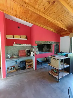 a room with a red wall with a fireplace at Loft de Montaña y Playa VenTeVeo in Atos Pampa