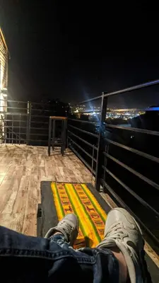a person sitting on the edge of a balcony at night at Casas de campo Traslasierra in Villa Cura Brochero