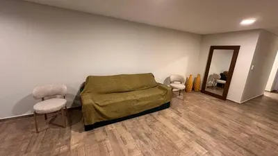 a bedroom with a bed and two chairs and a mirror at Guarida Güemes Suite in Cordoba