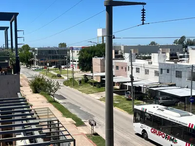 a white bus driving down a city street at Estadio Kempes Valle escondido Centro de Convenciones Amplio y Luminoso in Cordoba