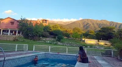 a woman standing next to a swimming pool at Casona de Montaña in Los Hornillos