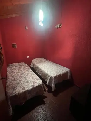 two beds in a room with a red wall at Casona de Montaña in Los Hornillos