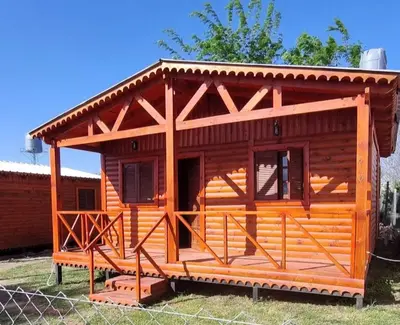 a log cabin with a porch and a fence at Cabañas para 4 personas M y M Cabañas in Villa Yacanto