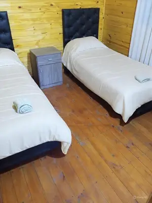 two beds in a room with a wooden floor at Cabañas para 4 personas M y M Cabañas in Villa Yacanto