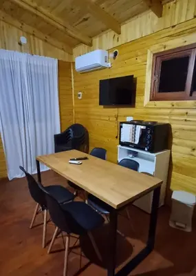 a dining room with a table and chairs and a television at Cabañas para 4 personas M y M Cabañas in Villa Yacanto
