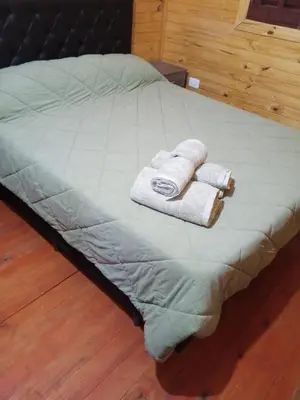 a bed with three towels on top of it at Cabañas para 4 personas M y M Cabañas in Villa Yacanto