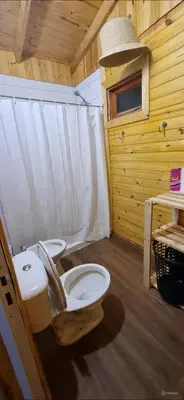 a bathroom with a toilet in a wooden cabin at Cabañas para 4 personas M y M Cabañas in Villa Yacanto