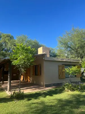 a house with a porch and a tree in the yard at Cabañas la Huerta in Las Tapias