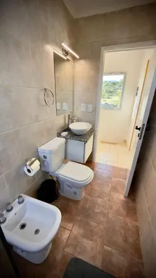 a bathroom with a white toilet and a sink at Villa Las Medulas - Los Ancares Resort in Mina Clavero