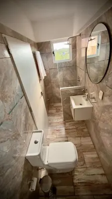 a bathroom with a toilet and a sink and a mirror at Villa Las Medulas - Los Ancares Resort in Mina Clavero