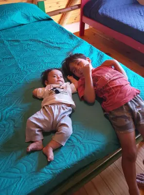 two young children laying on a bed at CABAÑAS L y L in Villa Santa Cruz del Lago