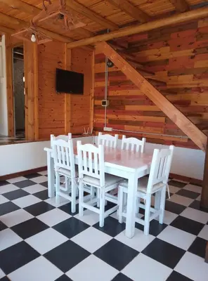a dining room with a white table and white chairs at CABAÑAS L y L in Villa Santa Cruz del Lago
