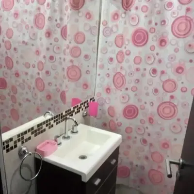 a bathroom with a sink and a pink shower curtain at Departamento en Villa Carlos Paz edificio tempo! in Villa Carlos Paz