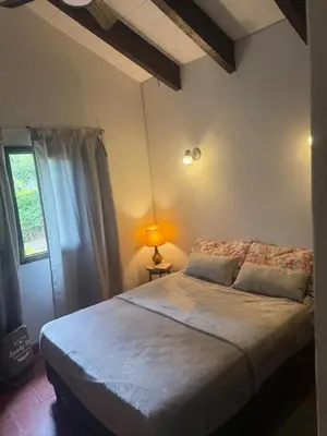 a bedroom with a bed and a lamp and a window at Casa en La Falda, Córdoba in Cordoba