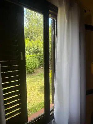 a window with a white curtain and a view of a yard at Casa en La Falda, Córdoba in Cordoba