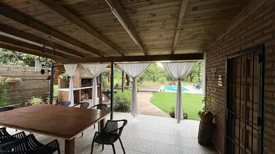 an outdoor patio with a wooden table and chairs at Casa de campo, Dique Chico in Villa Anizacate