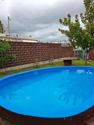 a large blue pool in front of a brick wall at Departamento cerca del rio in Villa Carlos Paz