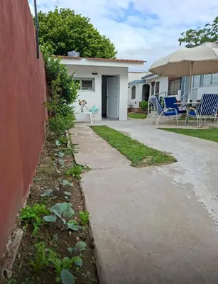 a sidewalk in front of a house with chairs and an umbrella at Departamento cerca del rio in Villa Carlos Paz