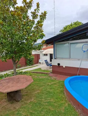 a house with a tree and a bench in the yard at Departamento cerca del rio in Villa Carlos Paz