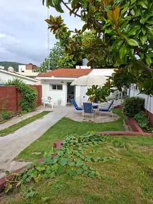 a yard with two chairs and an umbrella at Departamento cerca del rio in Villa Carlos Paz