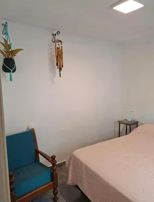 a bedroom with a blue chair next to a bed at Departamento cerca del rio in Villa Carlos Paz
