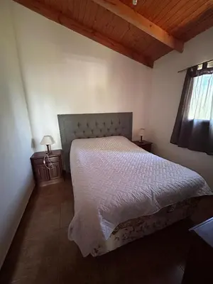 a bedroom with a bed with a white comforter and a window at Alma Ina in Villa Yacanto