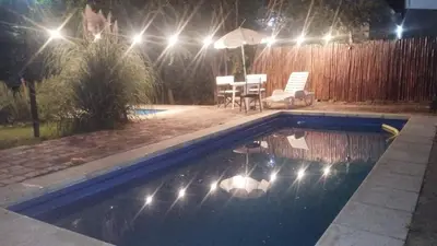 a swimming pool at night with a table and an umbrella at Cabañas de Ensueño in Cuesta Blanca
