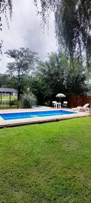a swimming pool in a park with a grass field at Cabañas de Ensueño in Cuesta Blanca