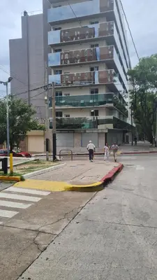 two people walking on a street in front of a tall building at Romina Cañada in Cordoba