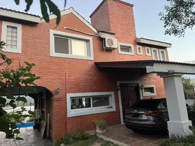 a red brick house with a car parked in the driveway at Casa con hermosa vista al lago in Villa Carlos Paz