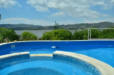 a large blue swimming pool with a view of the water at Casa con hermosa vista al lago in Villa Carlos Paz